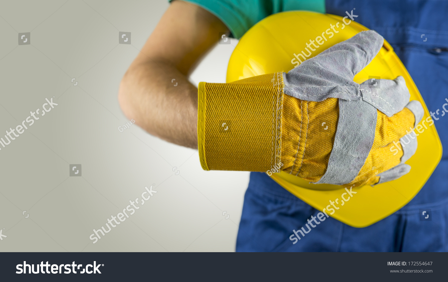 工人戴着防护手套拿着黄色安全帽或安全帽的概