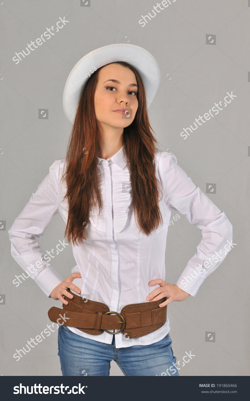 女孩在一件白色衬衣和牛仔裤上弯着腰,双手放