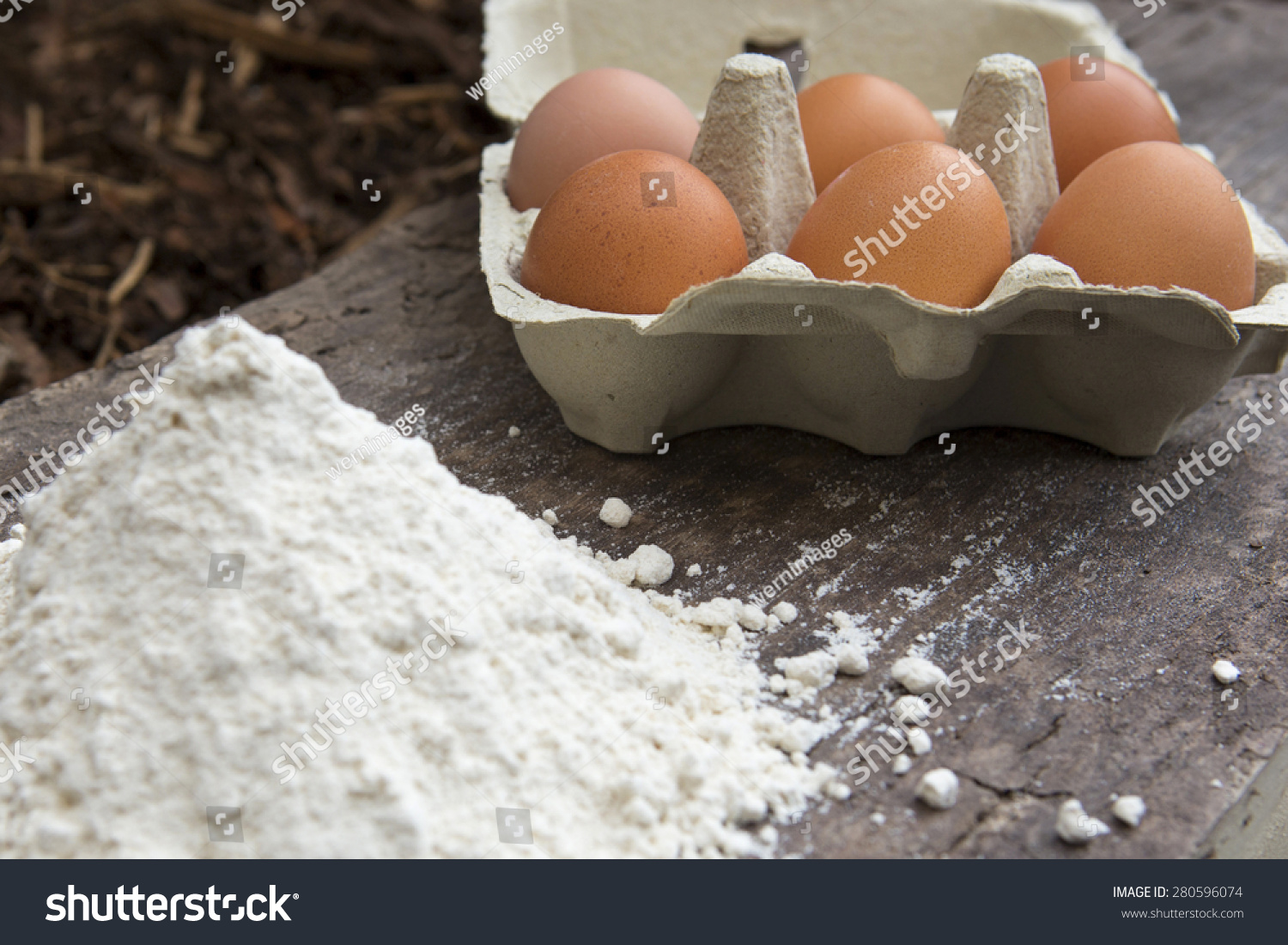 六个棕色的鸡蛋和一堆面粉的木板-食品及饮料
