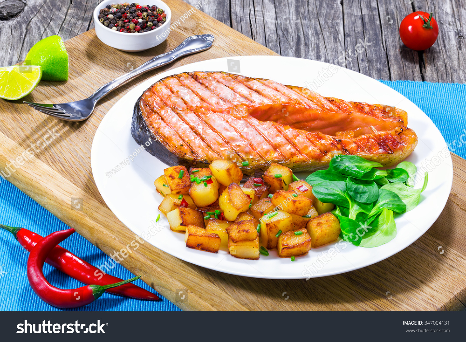 grilled salmon steak with fried potatoes and fresh green leaves