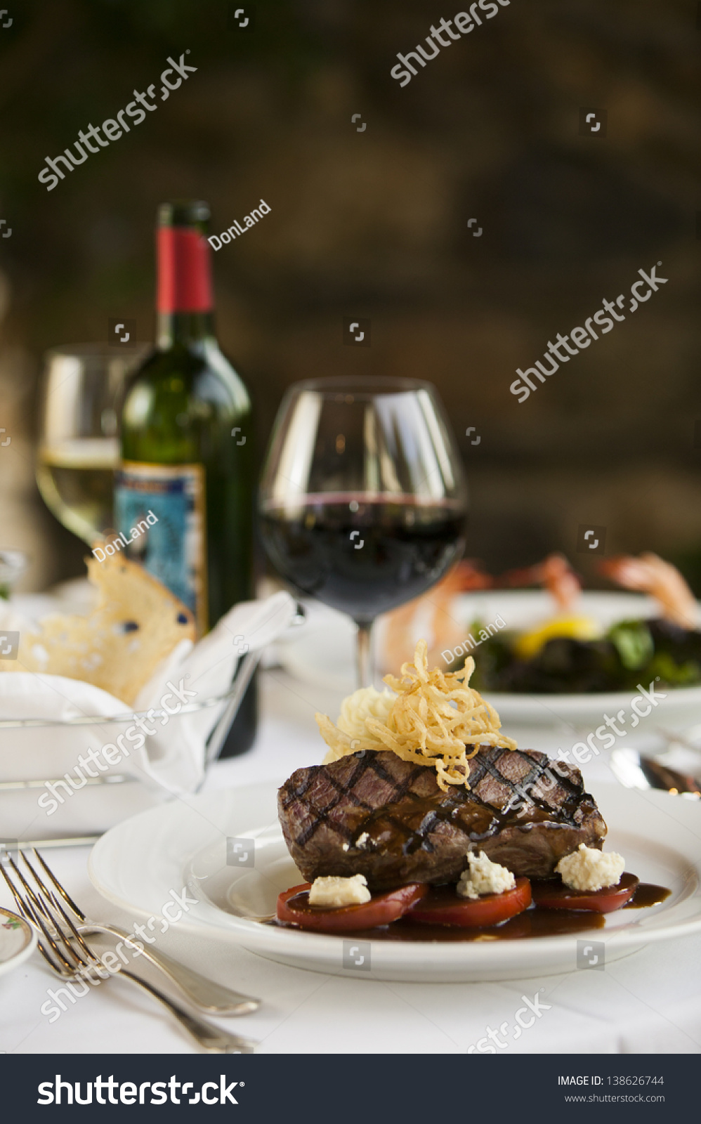 菲力牛排牛排晚餐和一瓶红酒在一个精致的餐厅设置.
