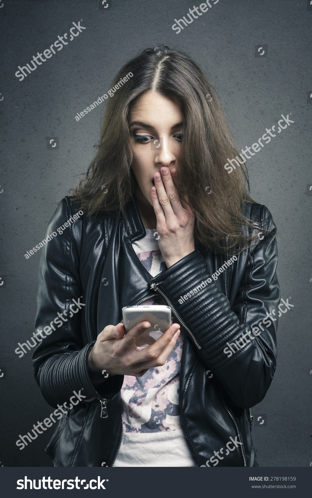 closeup portrait astonished young girl looking at phone seeing